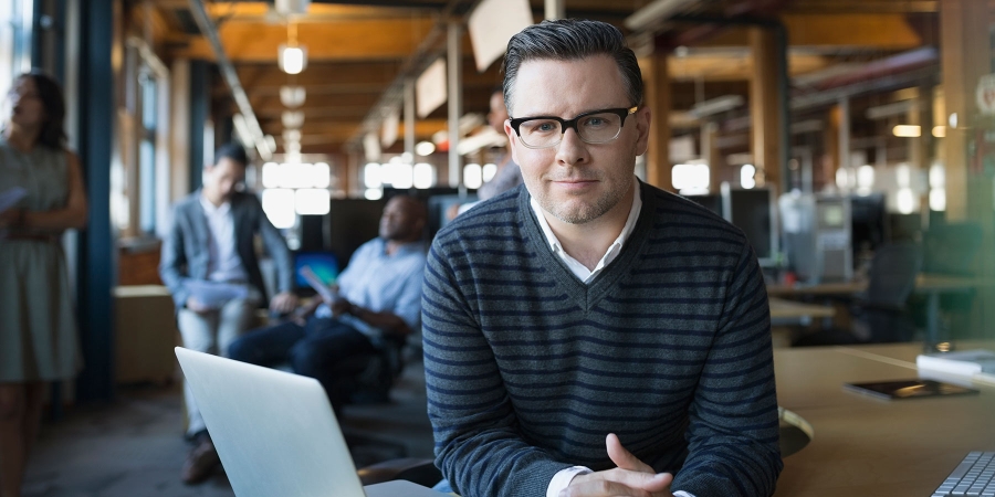 man wearing glasses sitting at his office desk